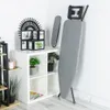 An ironing board and sleeve board are shown standing next to a white shelving unit with decorative items and plants. Voir les images du produit