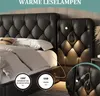 A close-up view of a black upholstered bed with integrated LED reading lamps and USB ports. Produktbild-Vorschau
