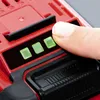 A close-up of a finger pressing a button on a red and black battery pack with three green indicator lights. Produktbild-Vorschau