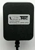A close-up view of a black power adapter with a label showing company information. Produktbild-Vorschau