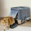 A cat is stepping out of a modern gray litter box with a clear lid and a scoop attached to the side. The litter box is placed on a white rug in front of a light-colored wall. Náhľad obrázku produktu