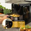 A person's hand is shown operating an air fryer, with food inside and vegetables in the background. A table with food is in the foreground. Produktbild-Vorschau