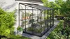 A greenhouse attached to a house, filled with plants and shelves. Produktbild-Vorschau