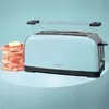 A light blue toaster with a stack of bread and butter on a light blue surface against a light blue background. Voir les images du produit