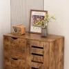 A close-up view of a wooden dresser with drawers and a cabinet, decorated with a vintage radio, a framed picture, and a vase of flowers. Podgląd zdjęcia produktu