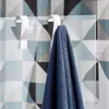 Two white hooks are attached to a glass surface, with one hook holding a blue towel. The background features a geometric tile pattern. Podgląd zdjęcia produktu
