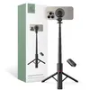 A product shot of a black selfie stick with a tripod base, a smartphone attached, and a remote control, next to its packaging. Produktbild-Vorschau