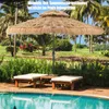 A thatched umbrella and lounge chairs by a pool in a tropical setting. Podgląd zdjęcia produktu
