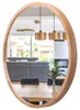A round wooden mirror reflecting a dining room with a sofa, dining table, chairs, and pendant lights. Produktbild-Vorschau