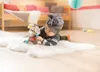 A baby wearing a turban is lying on a fluffy rug, playing with a stuffed donkey toy. Podgląd zdjęcia produktu
