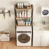 A laundry room scene with a washing machine, a shelf unit filled with laundry supplies, and a sink. Náhled obrázku produktu