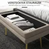 A storage bench with its lid open, revealing folded blankets and a book inside, placed next to a bed. Anteprima dell’immagine prodotto