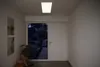 A hallway with a door and a window looking out into a garden at dusk. Produktbild-Vorschau