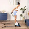 A woman is exercising with a stepper and resistance bands in a living room. Voir les images du produit