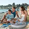 A family is having a picnic on the beach with an inflatable pool tray holding drinks. Náhled obrázku produktu