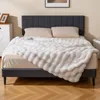 A bed with a white fluffy blanket and pillows, in a bedroom setting. Produktbild-Vorschau