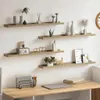 Four wooden shelves mounted on a white wall, decorated with various items. Náhľad obrázku produktu