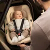 A father is shown adjusting a baby in a car seat inside a car. Náhľad obrázku produktu