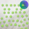 A collection of green snowflake-shaped stickers scattered on a textured white surface. Podgląd zdjęcia produktu