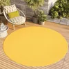 A round yellow rug on a wooden deck with a chair and plants. Voir les images du produit
