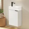 A white wall-mounted bathroom vanity with a black faucet and a white ceramic sink. A small wooden stool with a vase and a soap dispenser is to the left. Náhled obrázku produktu