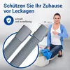 A woman is giving a thumbs up next to a washing machine and a basket of laundry, with a close-up of a drain hose in the foreground. Produktbild-Vorschau