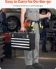 A person in a workshop setting is holding a black metal toolbox with multiple drawers. The person is wearing work clothes and a tool belt with various tools attached. Anteprima dell’immagine prodotto