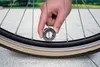A hand is holding a spoke wrench near a bicycle wheel. Produktbild-Vorschau