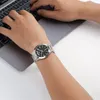 A person's wrist wearing a watch is shown next to a laptop. Podgląd zdjęcia produktu