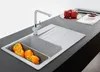 A kitchen sink with orange bell peppers in a colander, a faucet, and a countertop with red bell peppers and a small bowl of red paste. Podgląd zdjęcia produktu