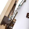 A close-up view of a metal chain and spring mechanism attached to a wooden structure, likely part of a folding attic ladder. Podgląd zdjęcia produktu