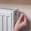 A hand is shown using a small key to turn a valve on a white radiator. Podgląd zdjęcia produktu