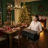 A woman is holding a black foldable cooler box in a dining room decorated for Christmas. Produktbild-Vorschau