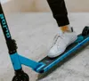 A person's foot on a blue stunt scooter. Náhľad obrázku produktu