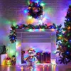 A festive Christmas scene with a fireplace decorated with lights, a wreath, and a Christmas tree. Produktbild-Vorschau