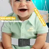Close-up of a smiling baby wearing a green shirt and a white safety belt, with marketing text overlays. Produktbild-Vorschau