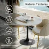 A round marble-top table with a black pedestal base and two chairs with gold legs are set up in a room with a view of a beach and ocean. Produktbild-Vorschau