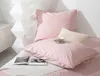 A neatly arranged bed with pink satin bedding, pillows, a small cup and saucer, and an open book. Podgląd zdjęcia produktu