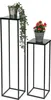Two black metal plant stands of different heights, each holding a potted plant. Anteprima dell’immagine prodotto