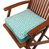 A close-up view of a teal and white patterned cushion on a wooden chair. Produktbild-Vorschau