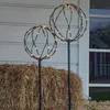 Two illuminated sphere decorations stand in front of a hay bale and a house. Produktbild-Vorschau