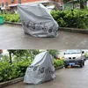 A gray bicycle cover with illustrations of bicycles and scooters is shown in two different outdoor settings. Voir les images du produit