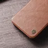 A close-up shot of a brown leather phone case with a metallic logo. Podgląd zdjęcia produktu