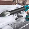 A person is using a cordless leaf blower to clear snow from a car windshield. Voir les images du produit