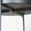 Close-up view of the underside of a black metal plant stand, showing the support structure and shelf. Produktbild-Vorschau