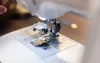A close-up view of the needle and presser foot of a sewing machine. Produktbild-Vorschau