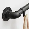 A close-up view of a black metal pipe fitting, part of a wall-mounted coat rack, with a beige fabric item hanging from it. Produktbild-Vorschau