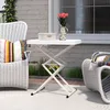 An outdoor patio scene with a white folding table and chairs. Produktbild-Vorschau