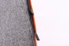 A close-up view of a gray felt cushion with an orange trim and a black zipper. Produktbild-Vorschau