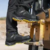 A person is climbing onto a piece of heavy machinery, wearing work boots. Produktbild-Vorschau